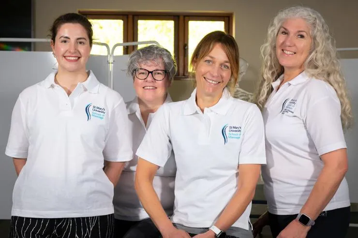 Four massage tutors from St Mary's School of Massage stand side-by-side smiling.