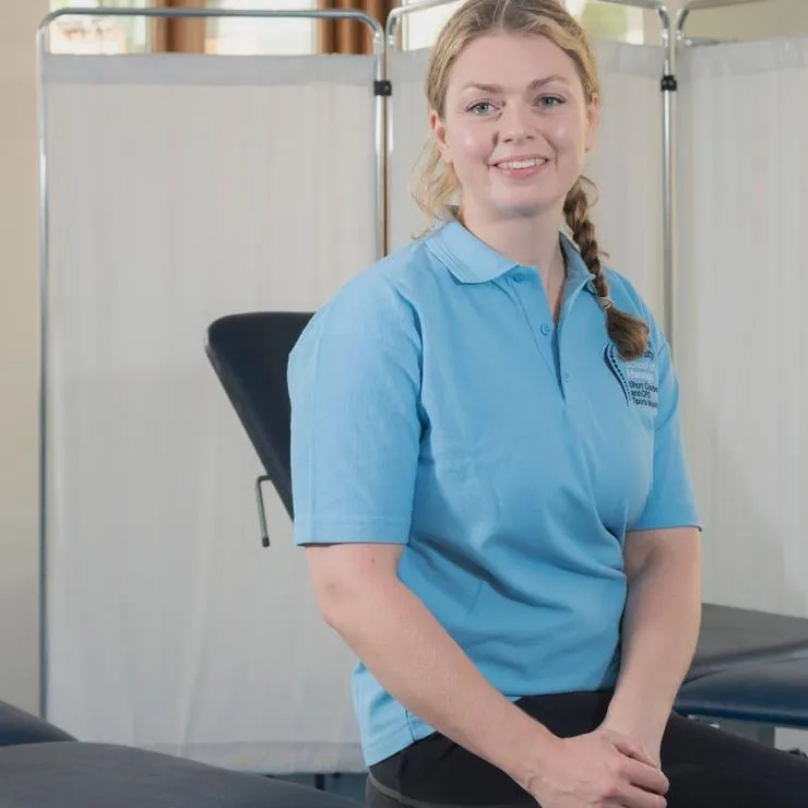 A massage student sits on a treatment table in St Mary's dedicated School of Massage.