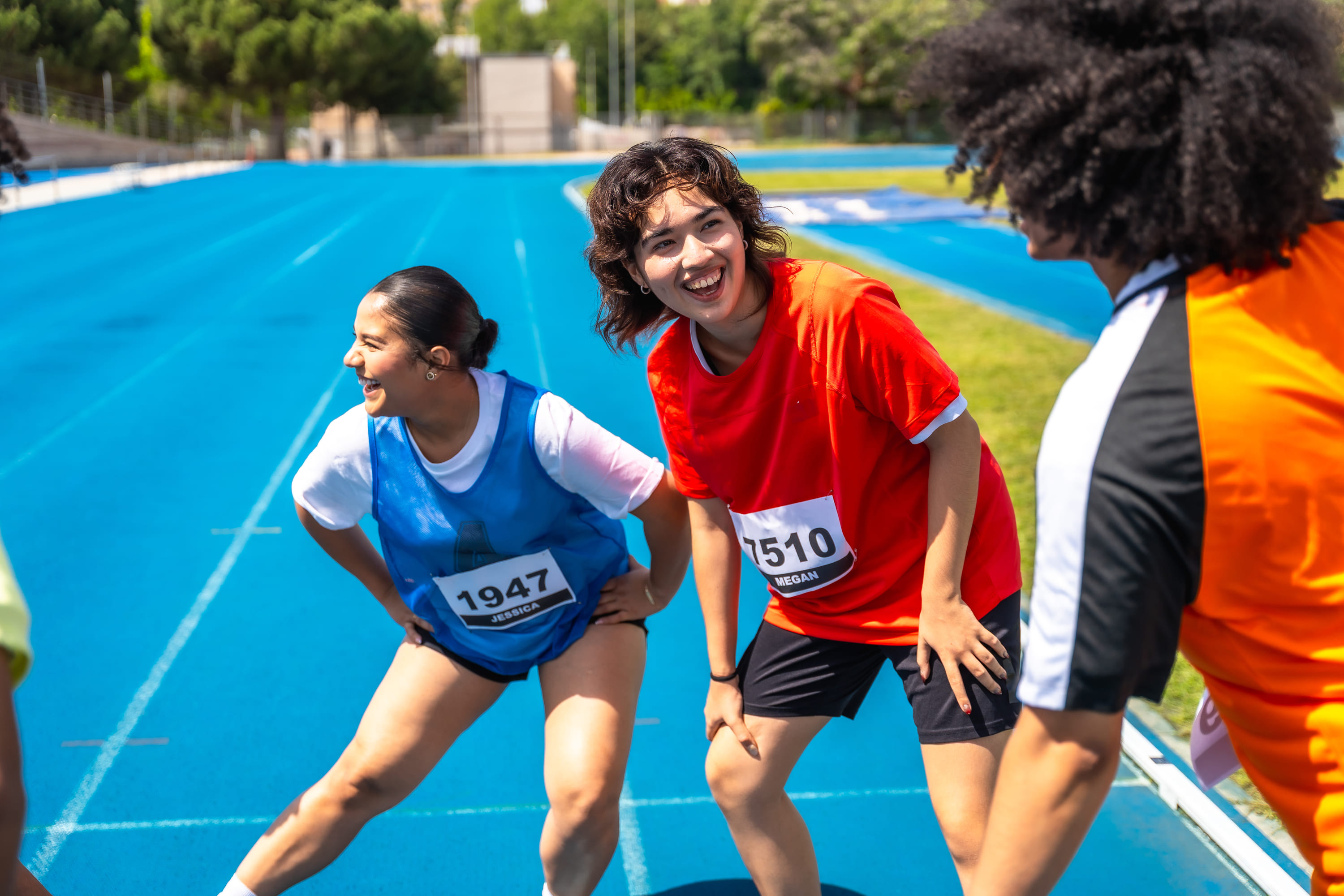 Students smiling while stretching on the running track.