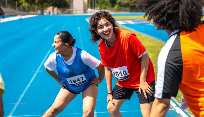 Students smiling while stretching on the running track.