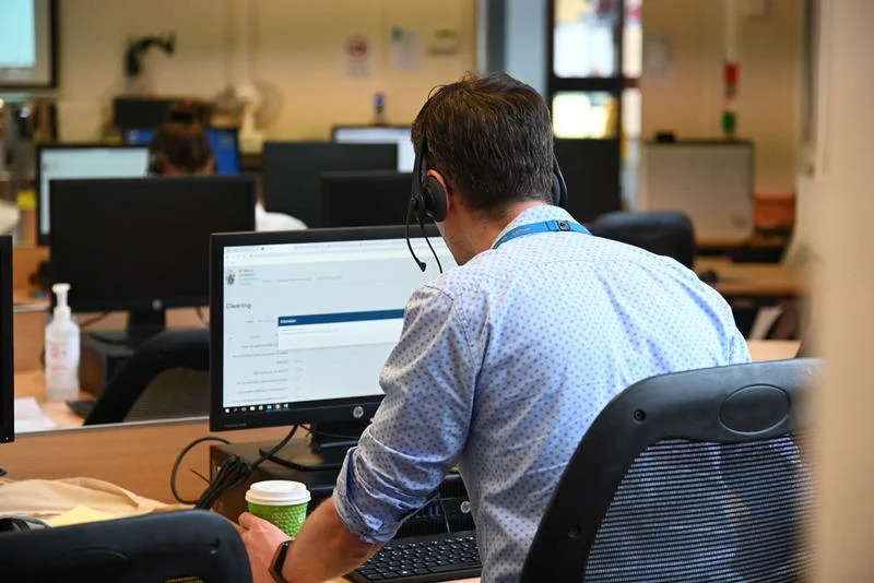 Person sitting at a desk working on a computer in an office environment.
