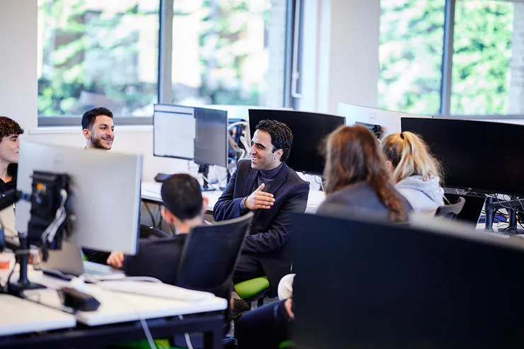 A Computer Science lecturer speaking with a group of students.