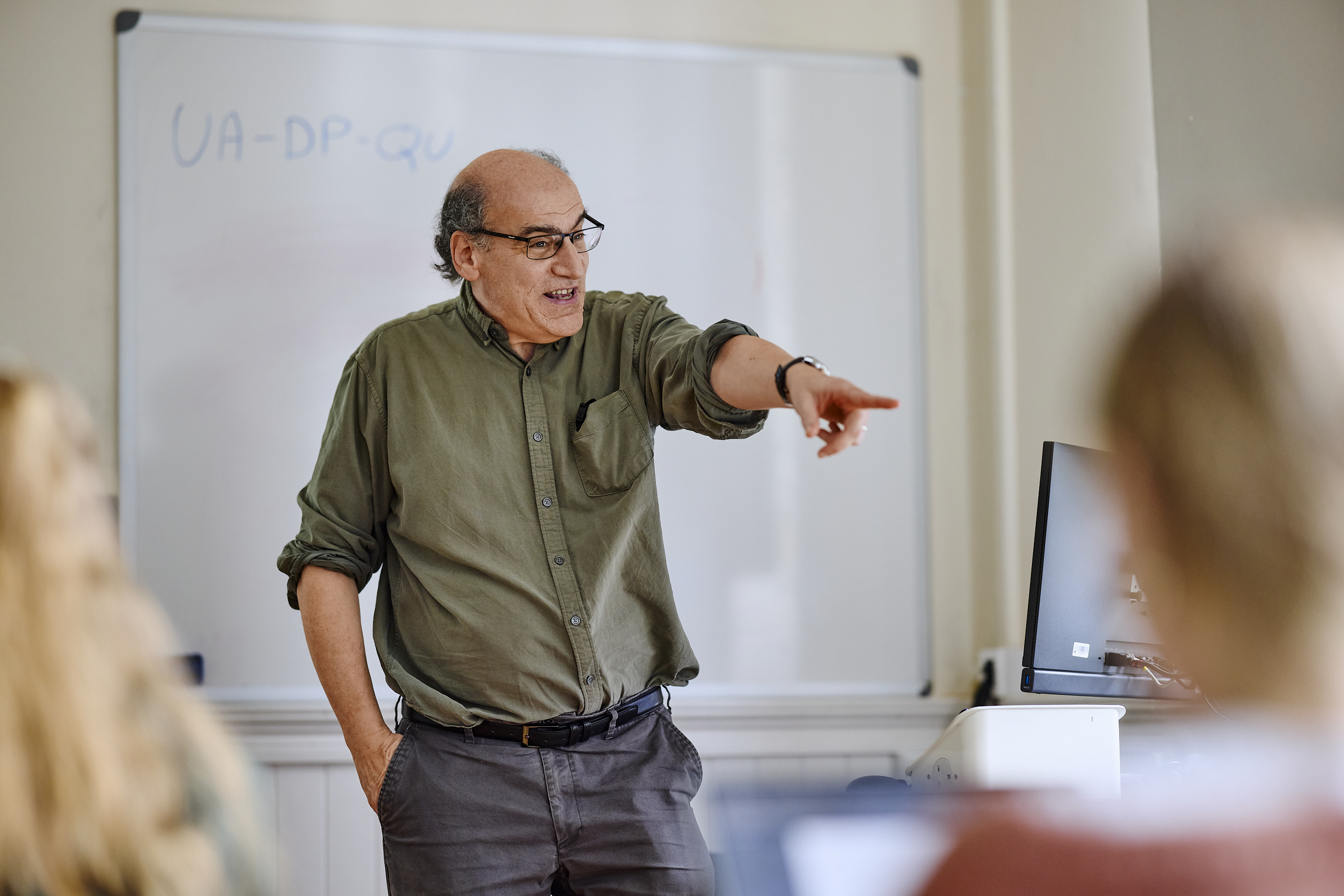 Creative writing tutor stands in front of a class, pointing excitedly at a student.