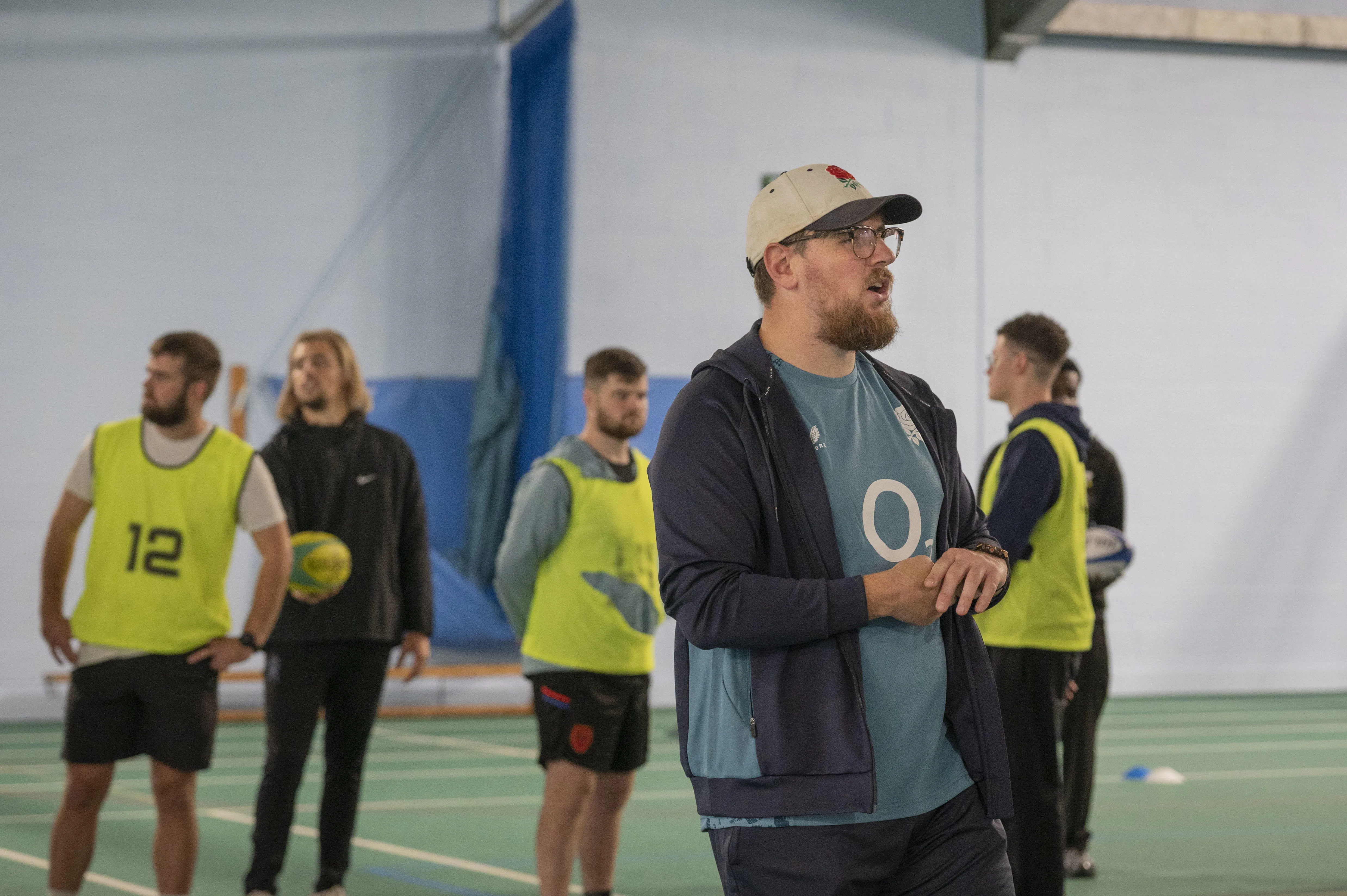 A sports coach leading a session with students.