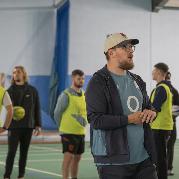 A sports coach leading a session with students.