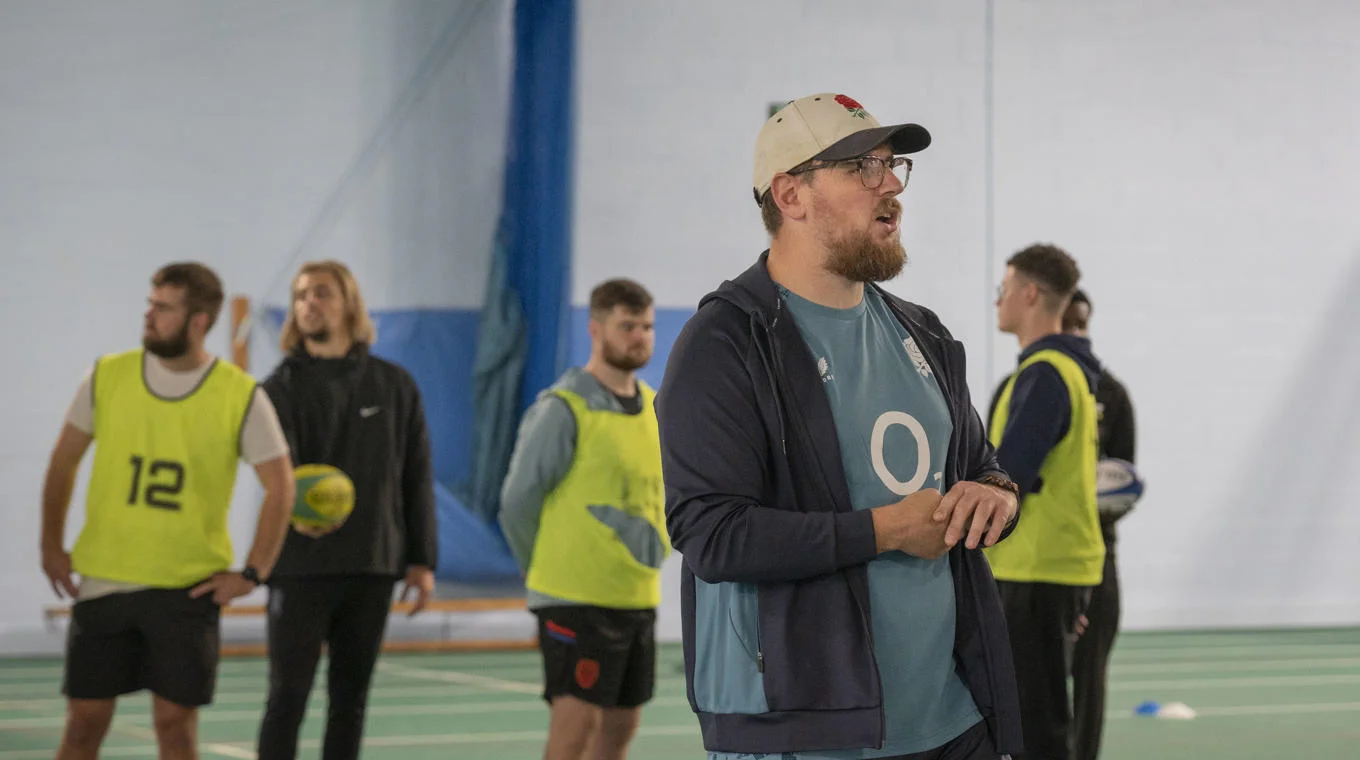 A sports coach leading a session with students.