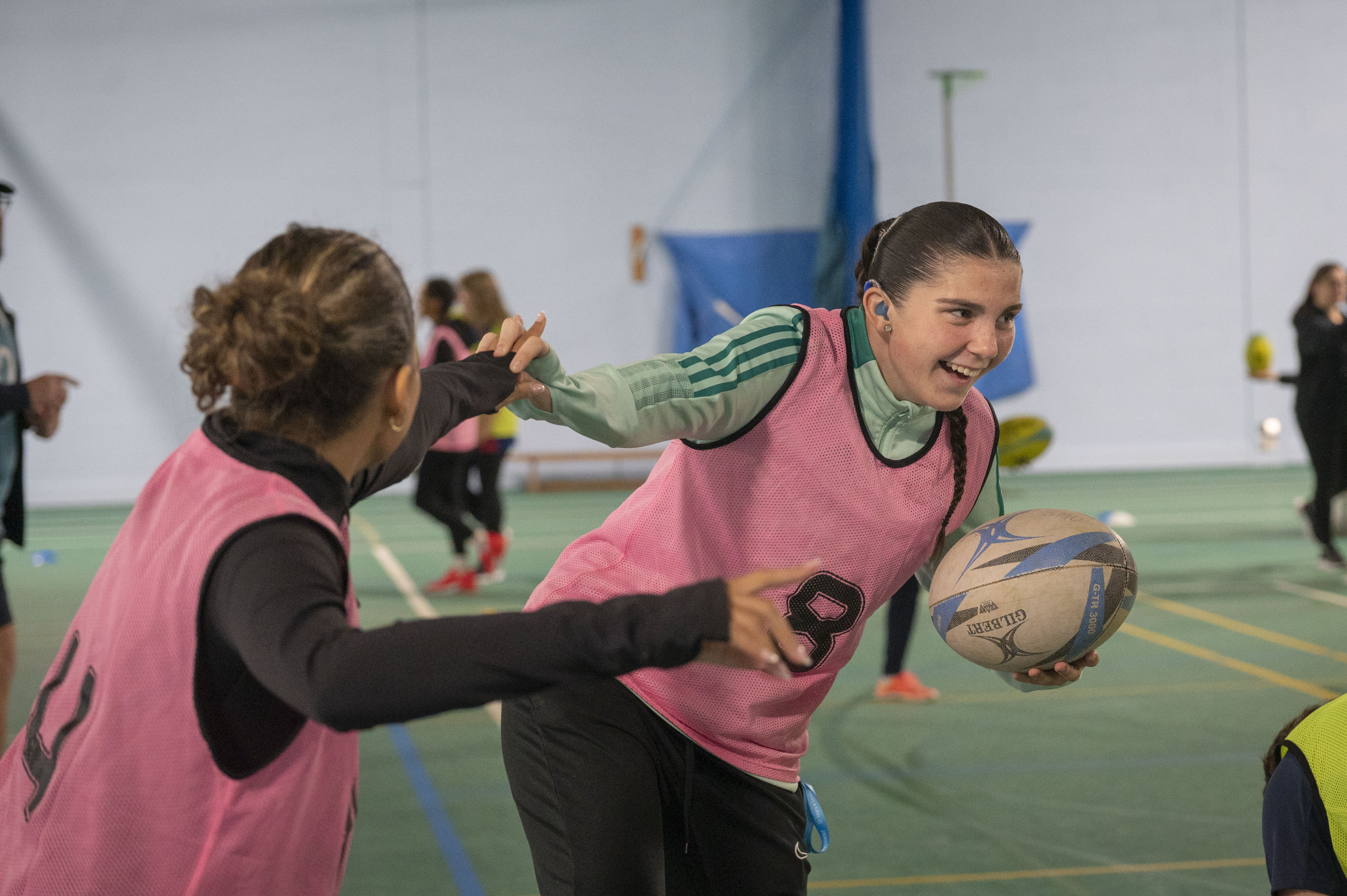 Students playing touch rugby inside the tennis hall.