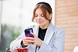 A business management student smiles as she looks at her mobile phone.