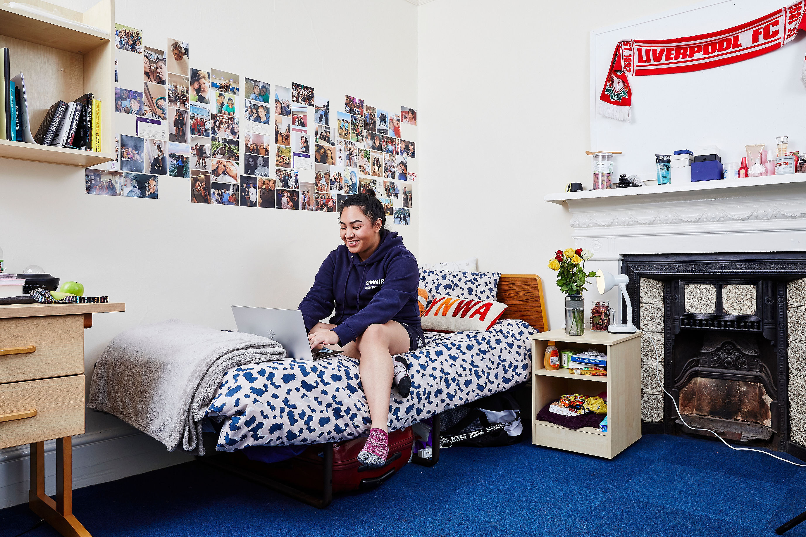 A student sat on the bed in her room.