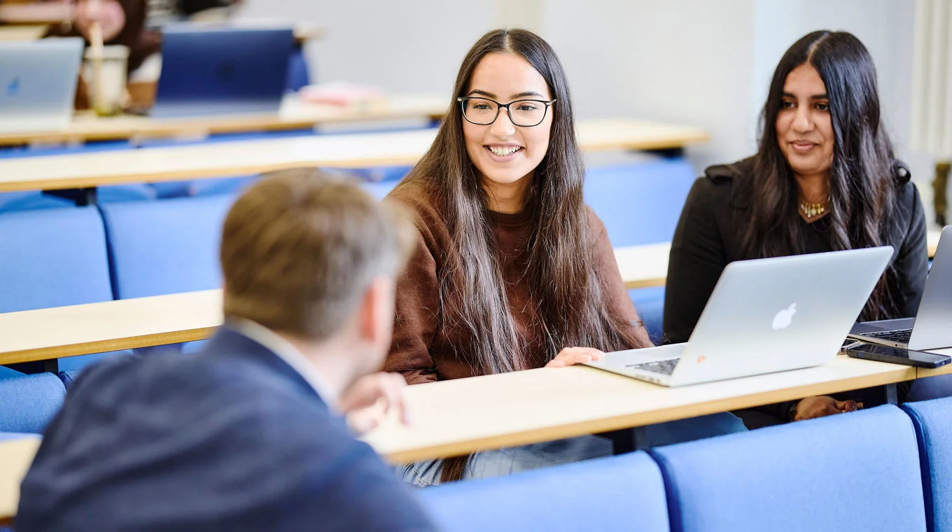 group of students smiling around laptop