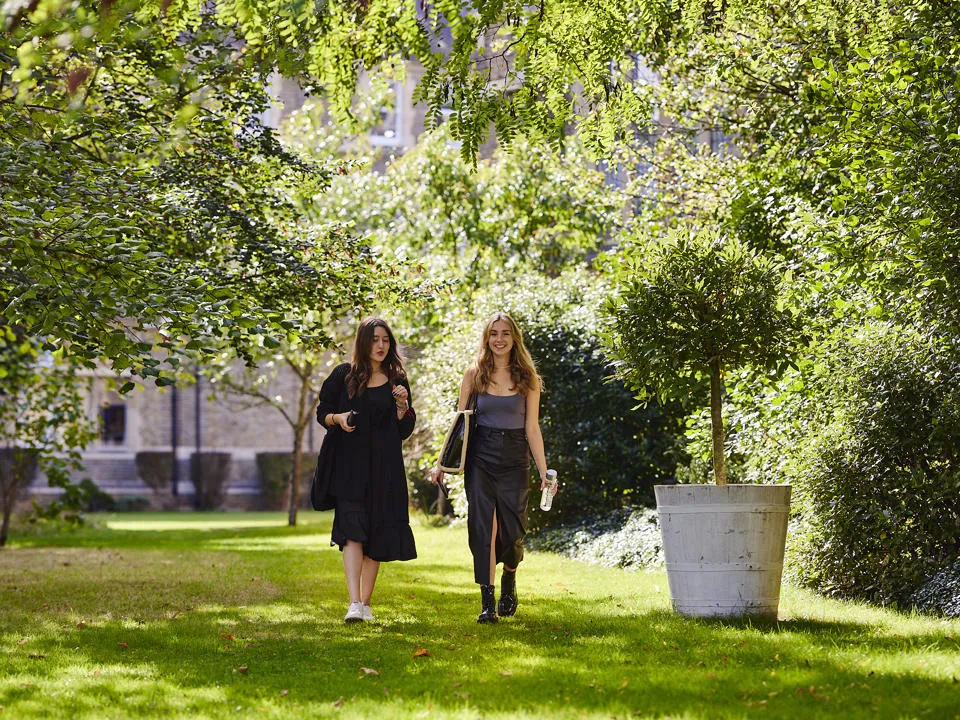 2 students walking in green campus grounds