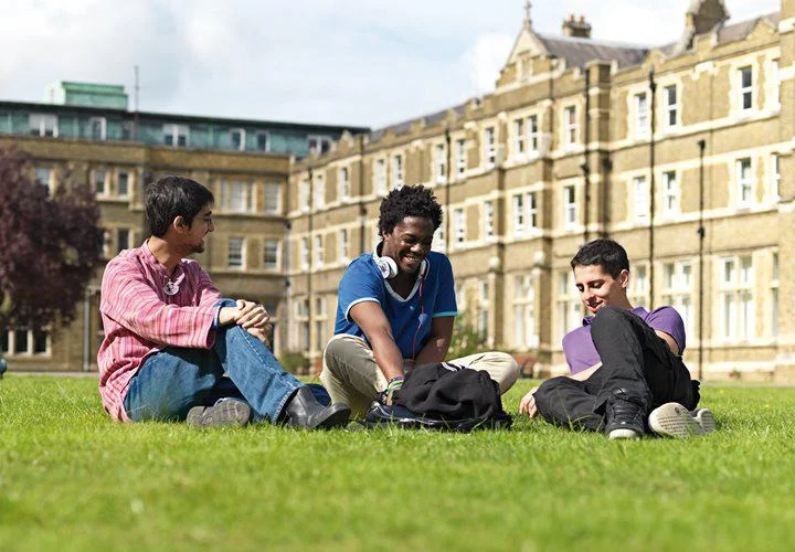 Three international students sat outside on the grass.