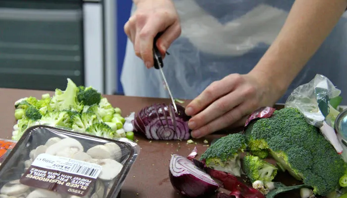 Person cutting up an onion in a nutrition class