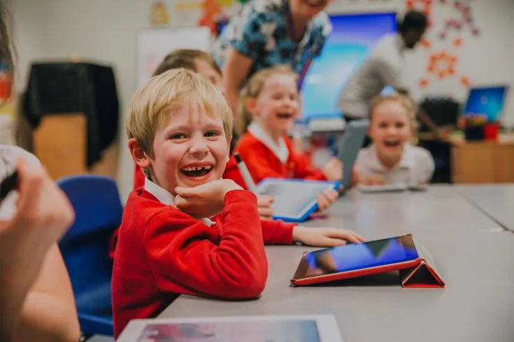 Children sitting in a classroom laughing and having fun while learning.
