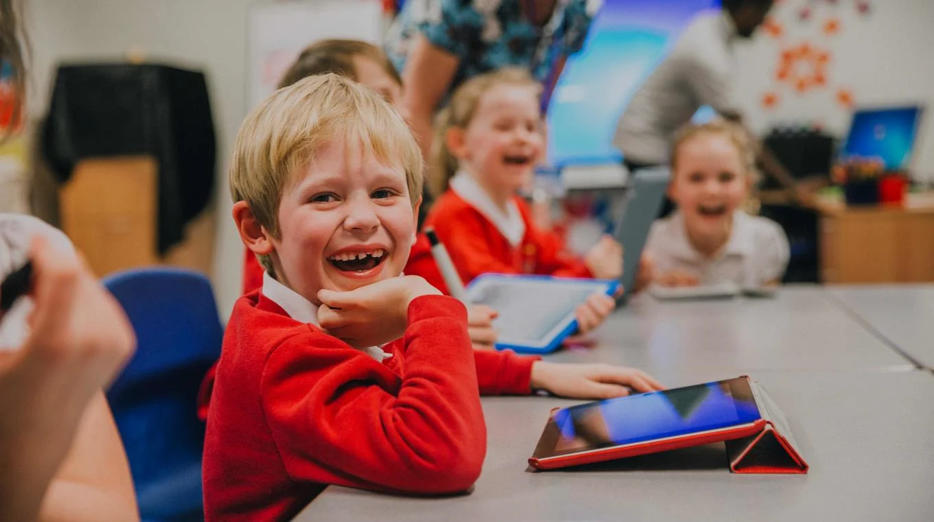 Children sitting in a classroom laughing and having fun while learning.