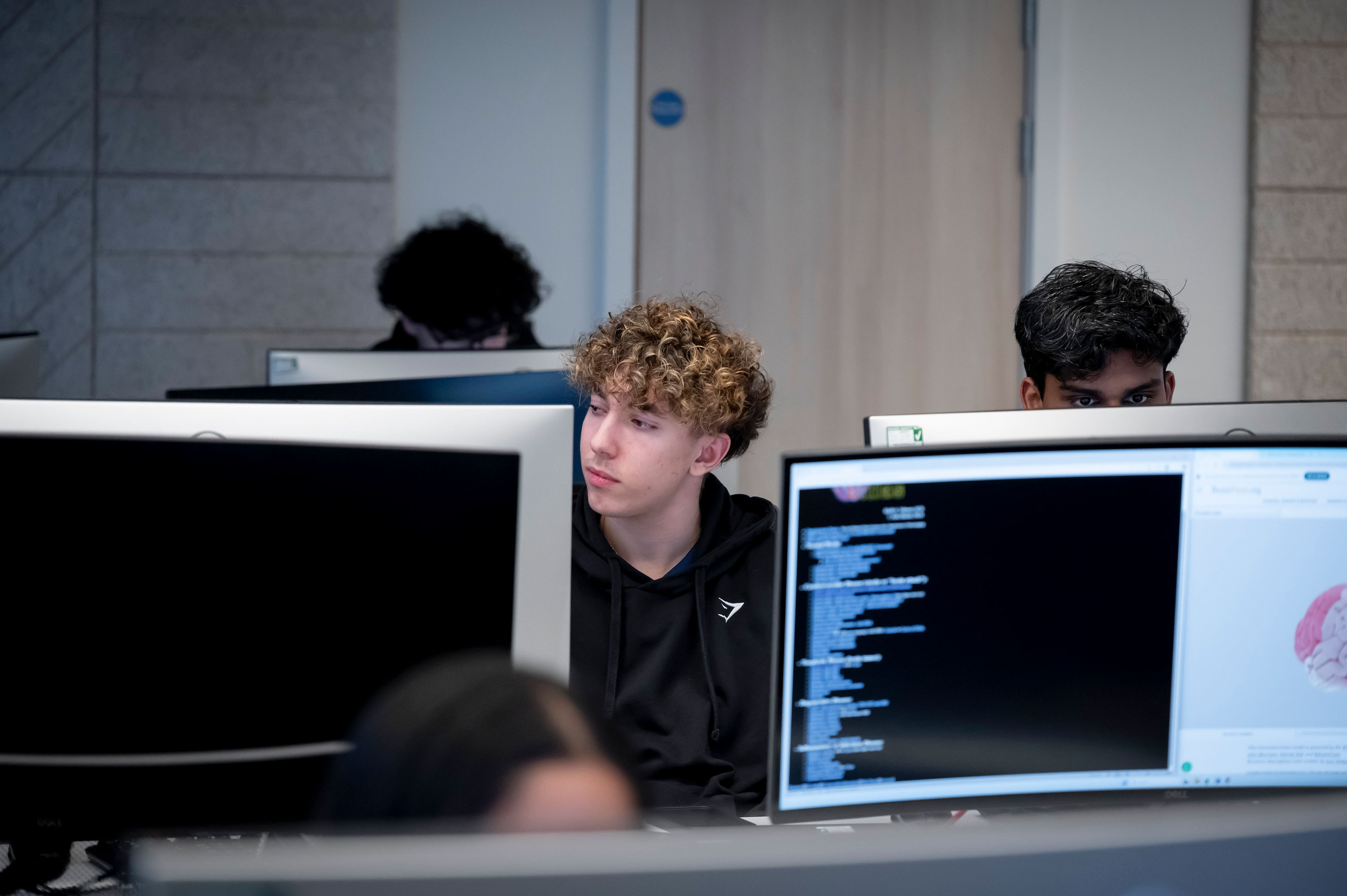 Male psychology student in a computer room with other students.