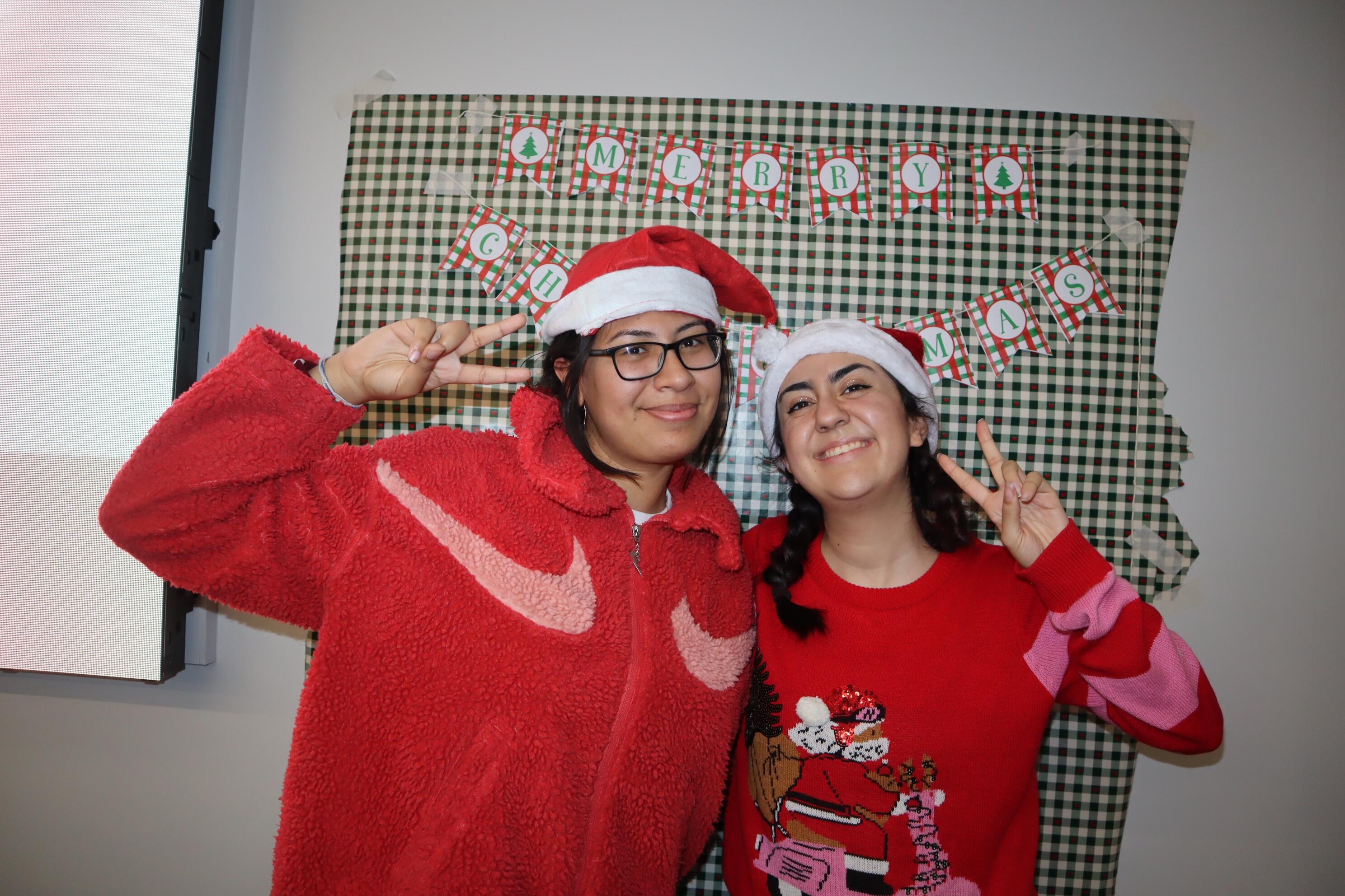 Two students from St Mary's University wear Santa hats and make a peace sign.