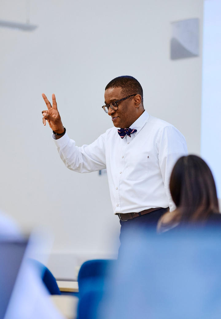 Kofi business lecturer teaching with hand gesture