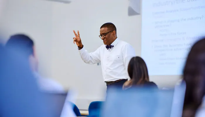 Kofi business lecturer teaching with hand gesture
