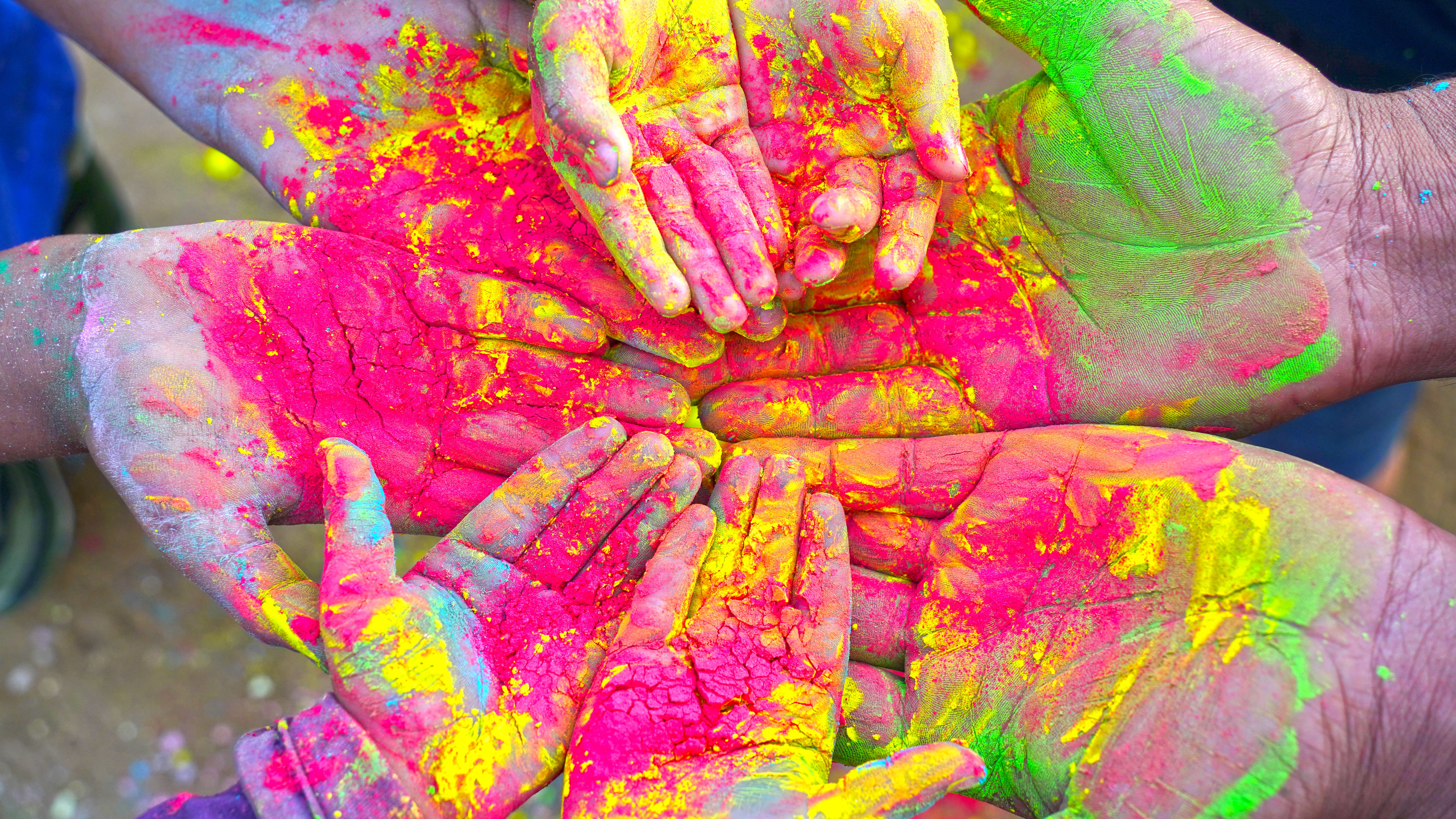 A circle of hands covered in bright paint powder.