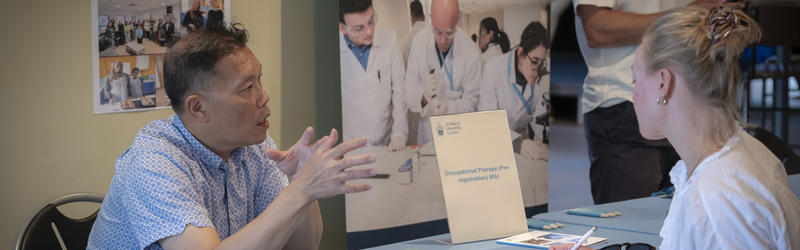 A lecturer talking to a student at an Open Day.