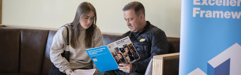 A student and parent looking through the Open Day booklet.