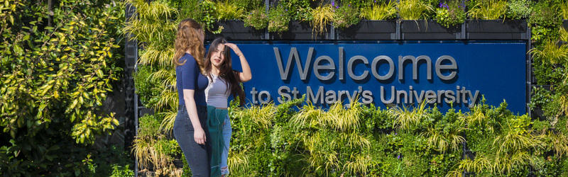 Students walking by the welcome sign to the university.