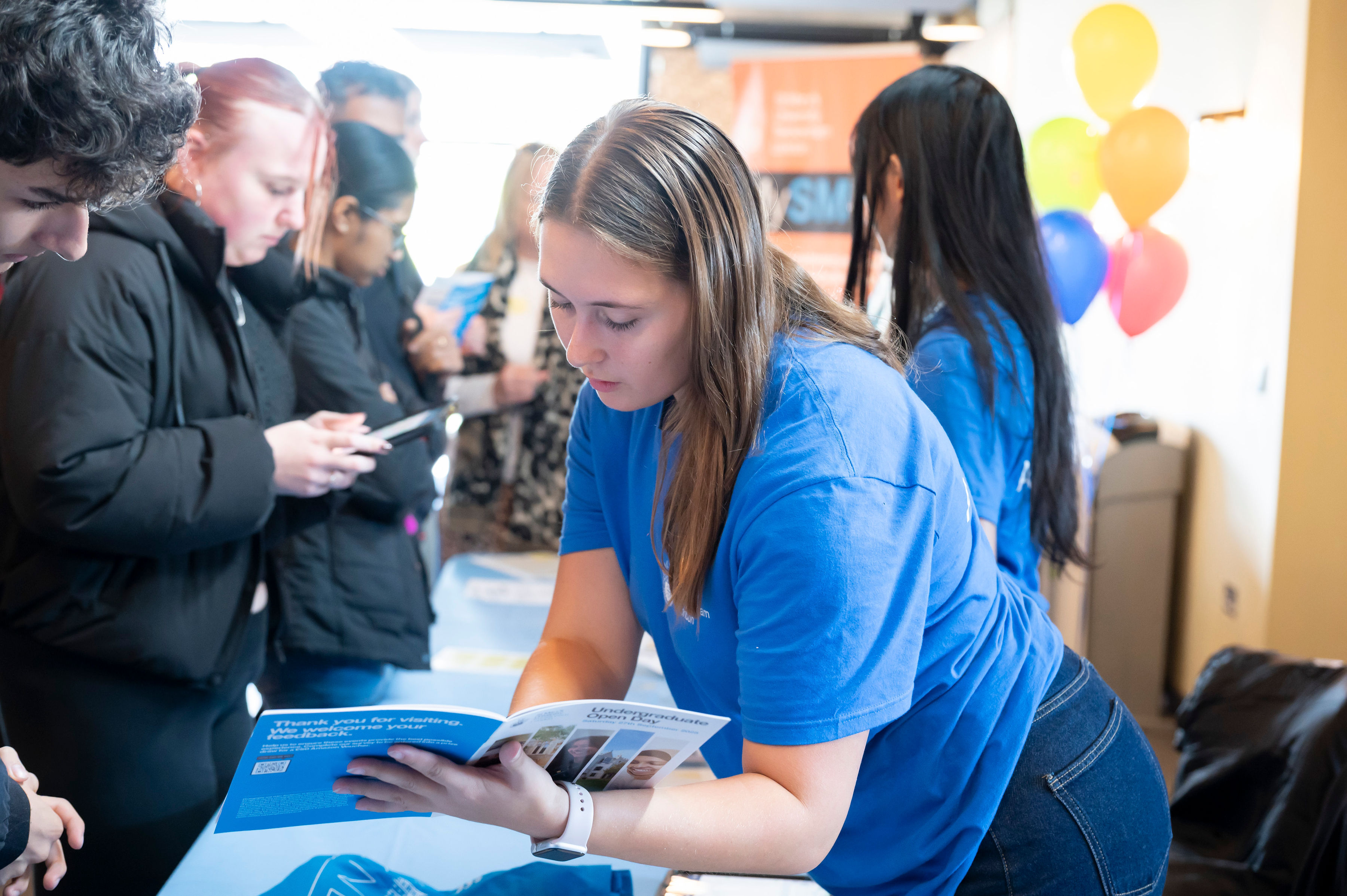 A Student Ambassador looks through a brochure with a prospective student during an Open Day at St Mary's University.