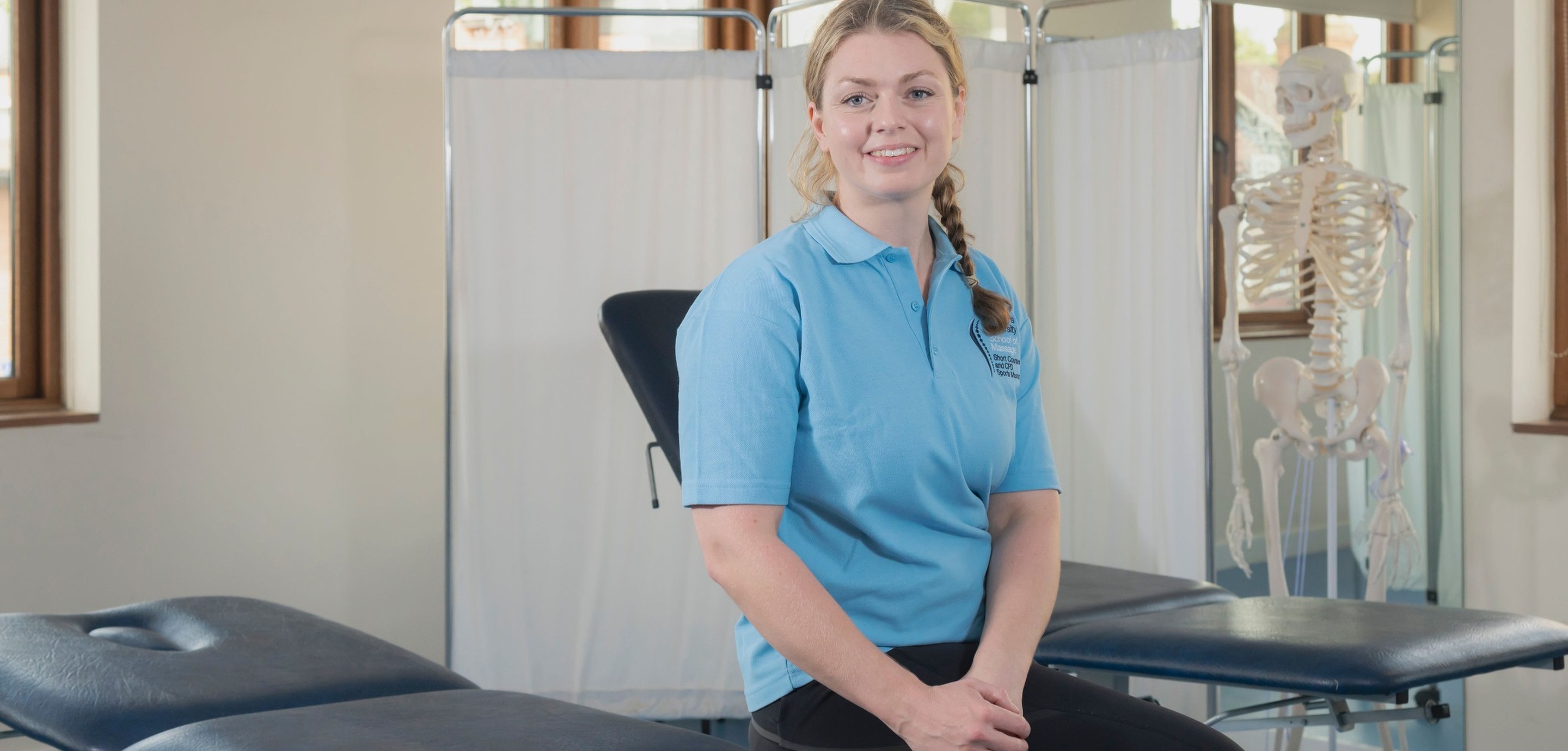 A massage student sits on a treatment table in St Mary's dedicated School of Massage.