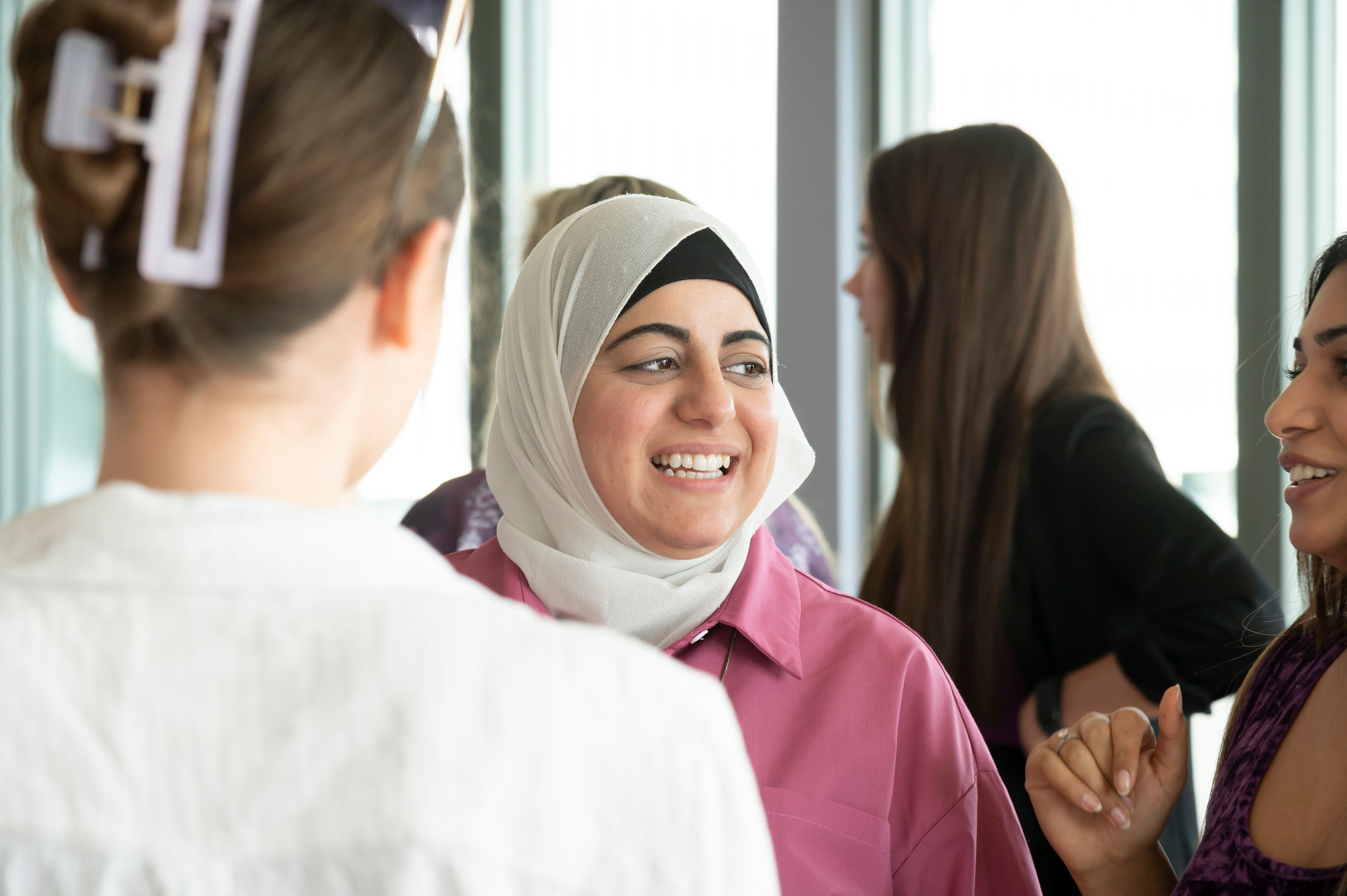 Three women smiling and engaging in a conversation.