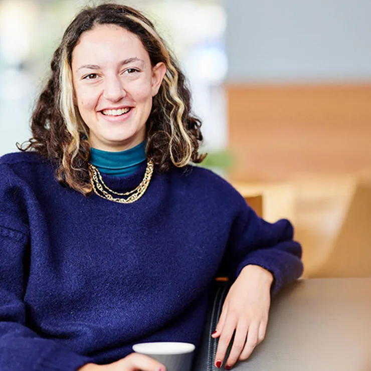 Student smiling while sat in the Dolce Vita Cafe with a coffee.