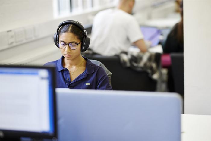 A student wears headphones and uses a St Marys computer.