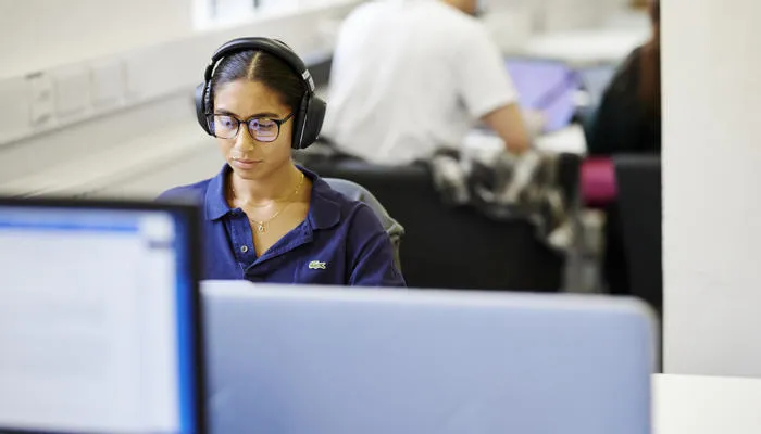 A student wears headphones and uses a St Marys computer.