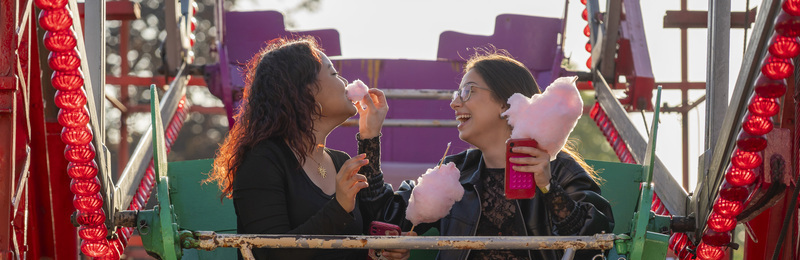 Students sat on a ride at the Summer Ball eating candy floss