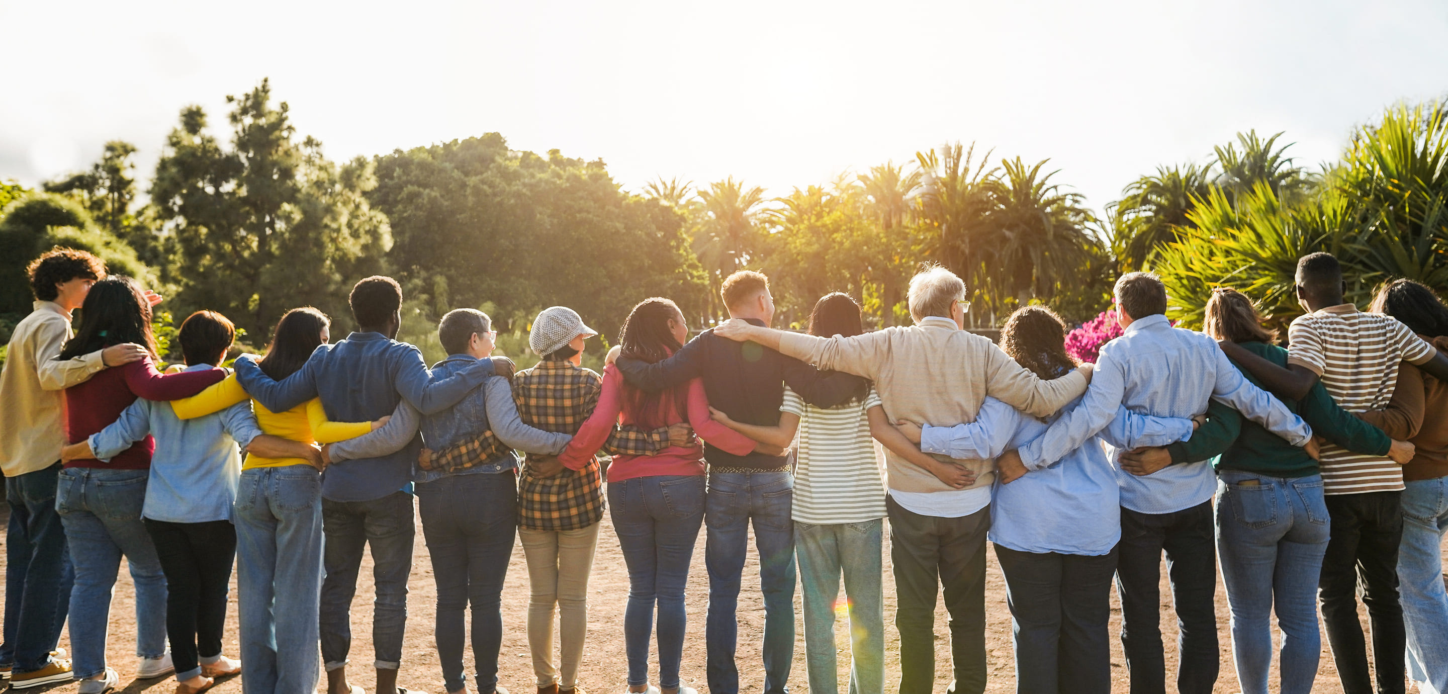 Students watch the sunset with their arms around one another.