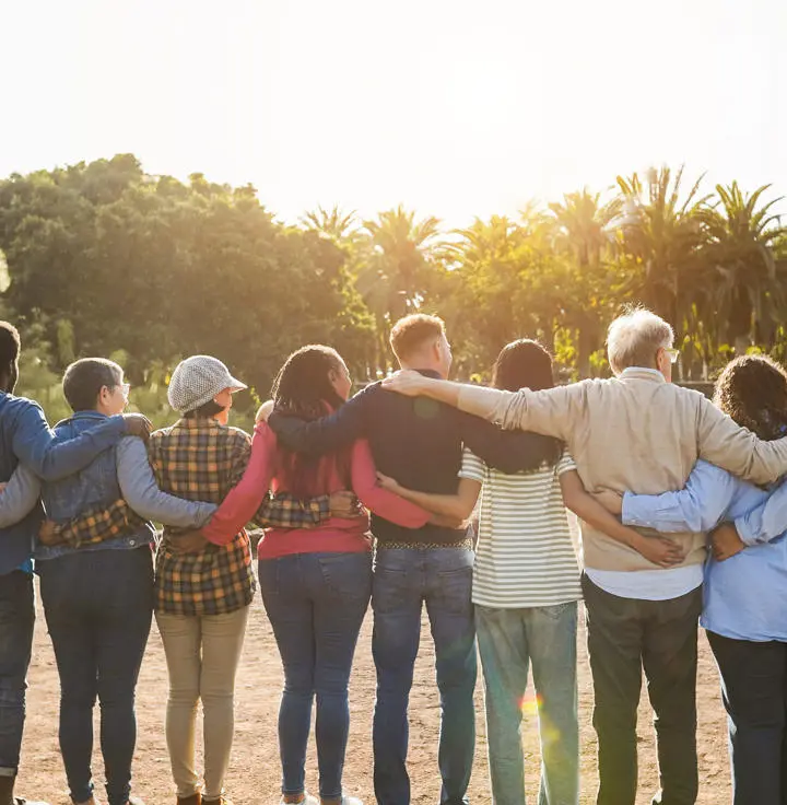 Students watch the sunset with their arms around one another.