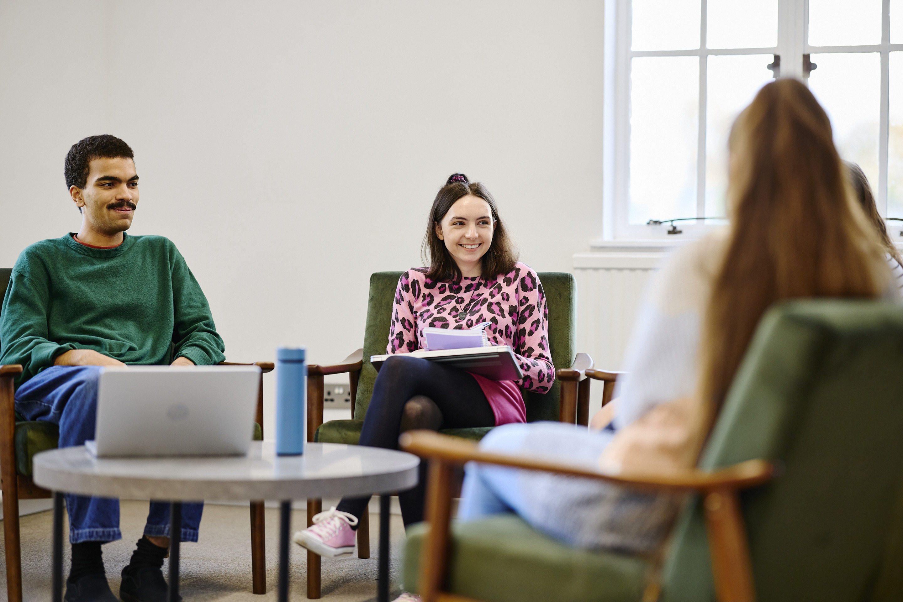 Three students sat around a table in the Living Room.