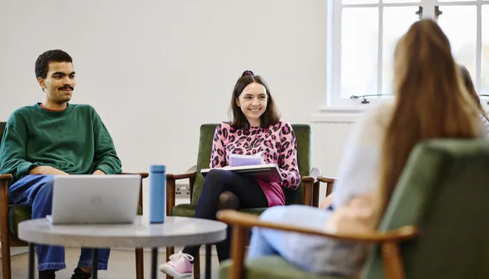 Three students sat around a table in the Living Room.