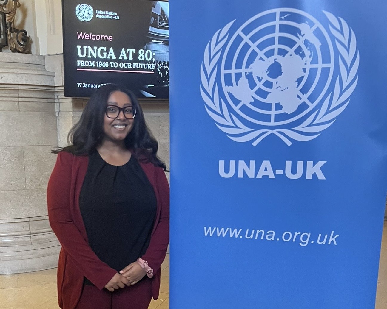 A master's student from St Mary's University stands beside a blue banner while attending a UN event.
