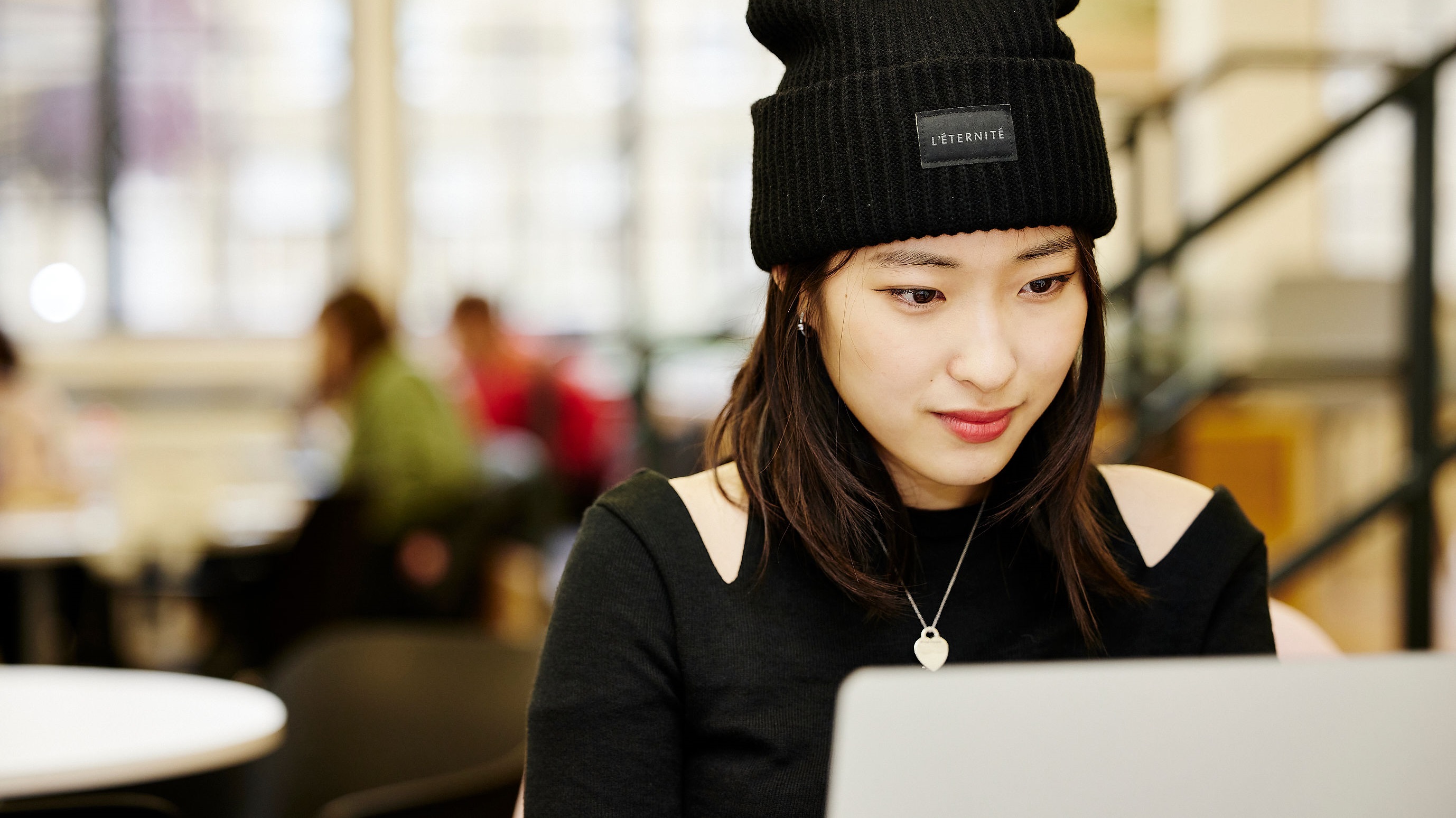 A student smiles softly as they work on a laptop.