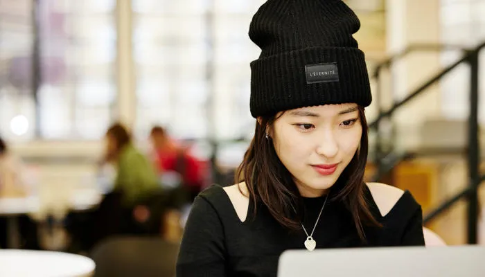 A student dressed in all black works on their laptop.
