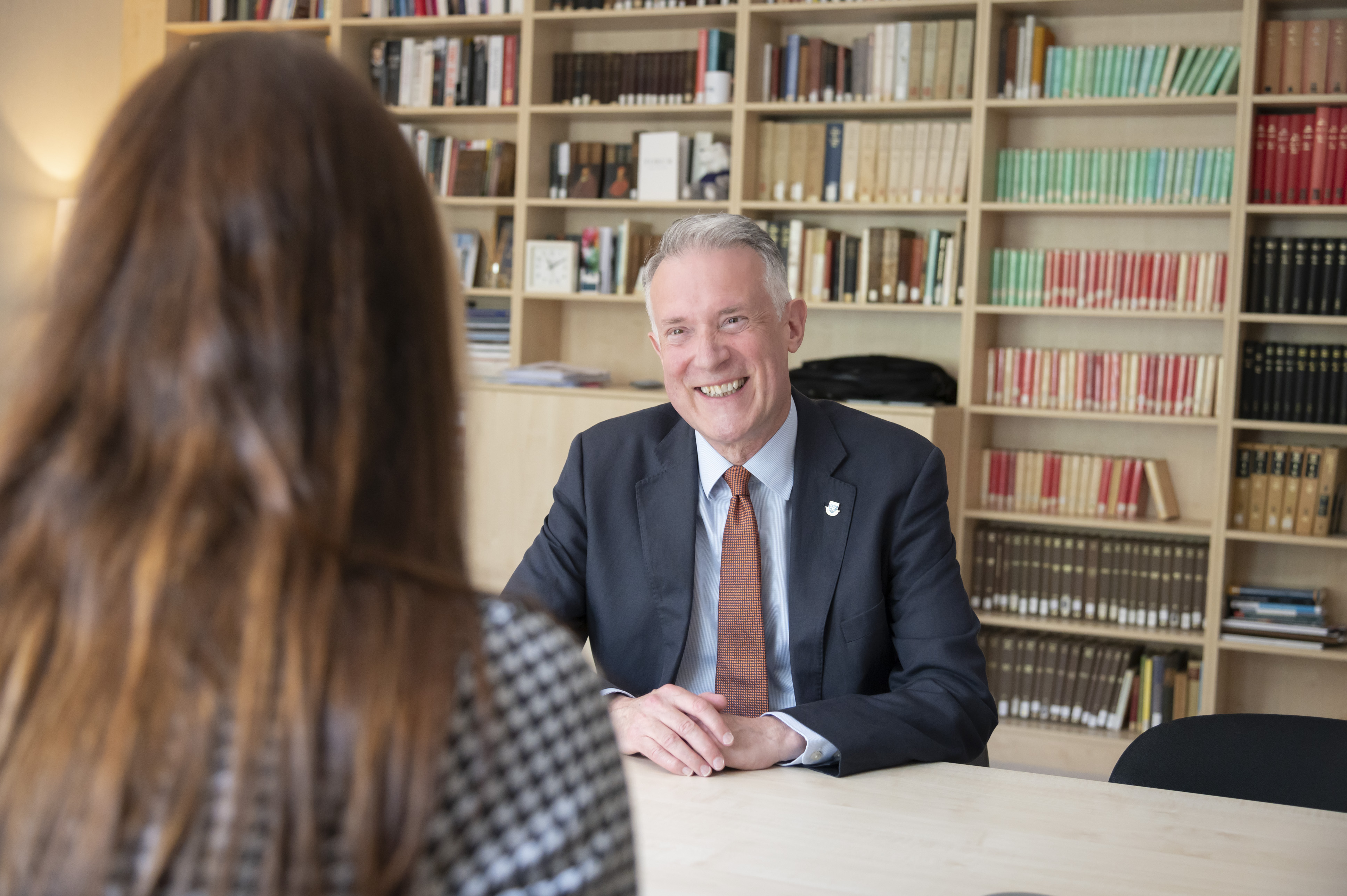 The Vice Chancellor smiling towards a lady sat opposite him.
