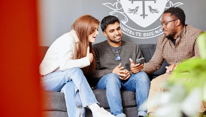 students chatting looking at phone on couch