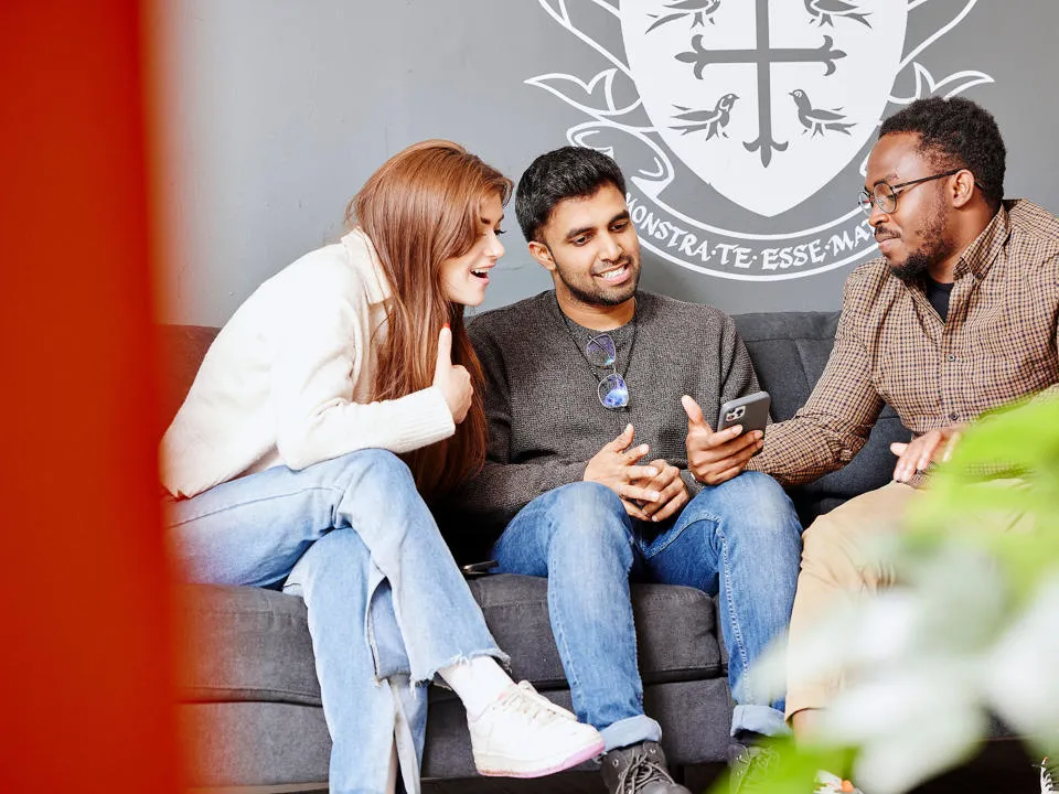 students chatting looking at phone on couch