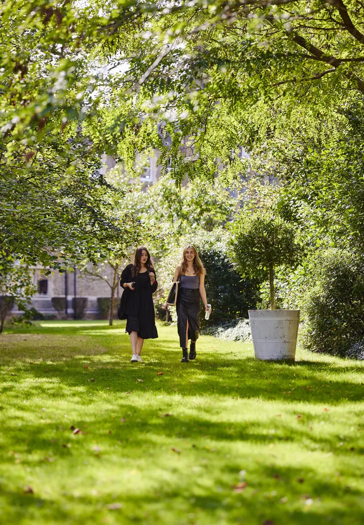 2 students walking in green campus grounds