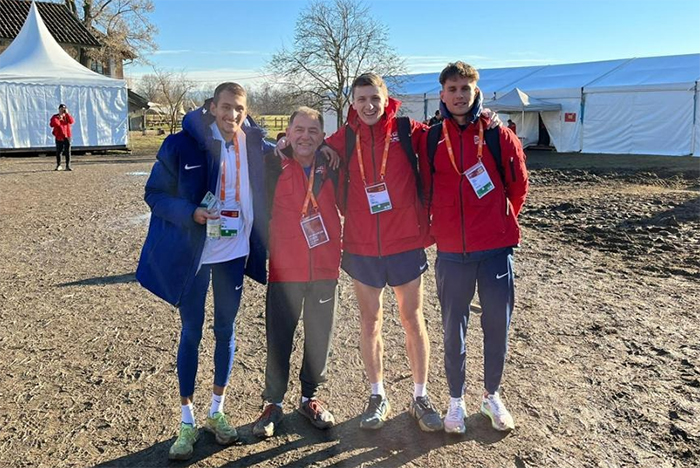 Mick Woods with three St Mary's athetes in team Gb coats in front of two marquees at championship venue