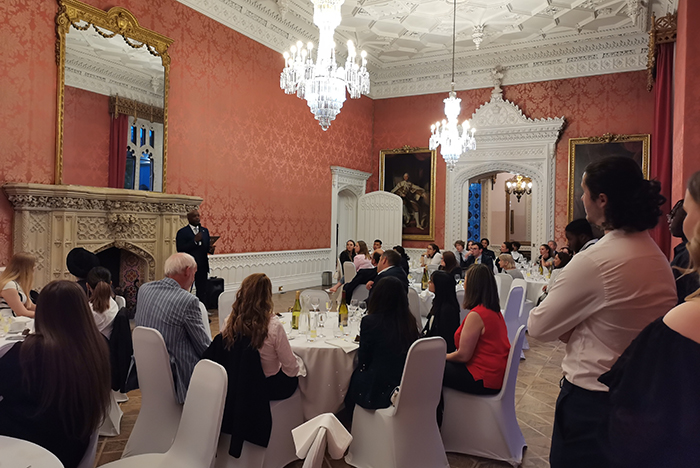 Students at dinning tables in waldegrave drawing room watching guest speak at lectern 