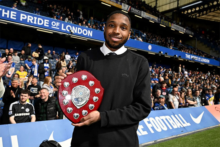 Adam Semple holding trophy in front of full stand at Stamford Bridge