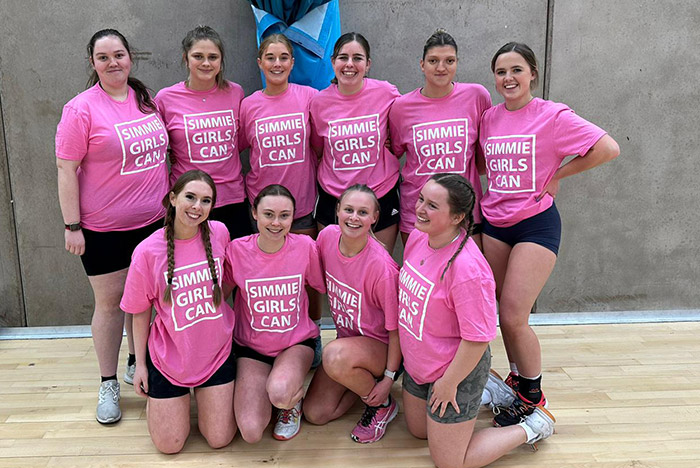 group photo of students wearing pink Simmies Girls Can t-shirts in sports halls