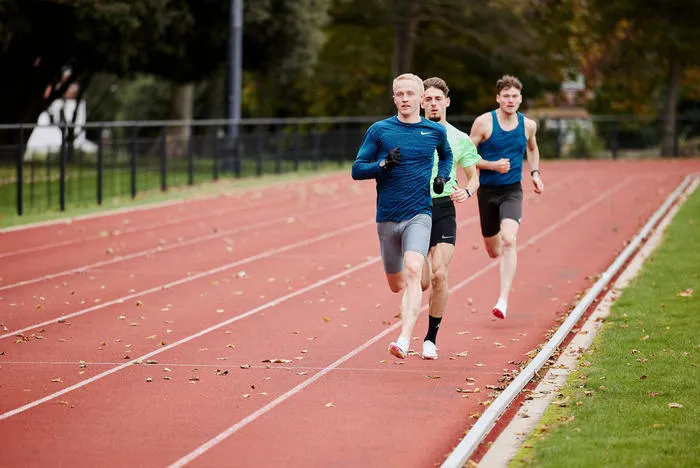 Three students running on the running track.